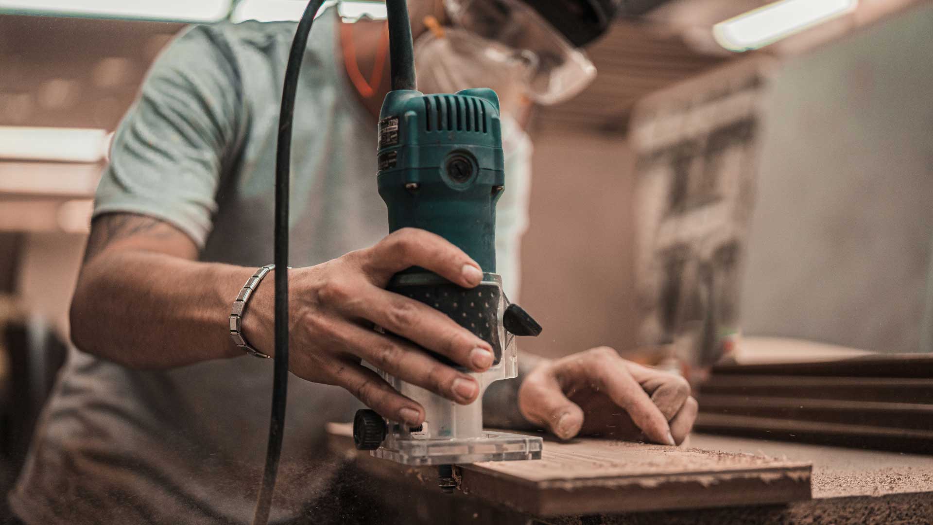 Mundpropaganda: Handwerker arbeitet mit einer Oberfräse an einem Holz Werkstück
